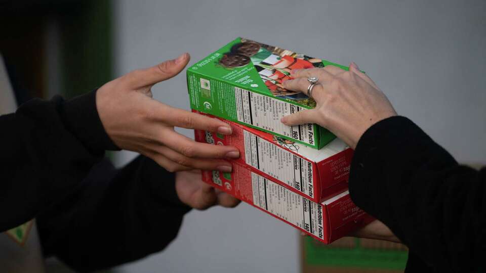 Girl Scout Sophie Kestel hands a customer boxes of cookies made through a traditional walk up purchase, through the troop is combining new technologies through Doordash along with traditional methods to sell cookies in Albany, California, on Saturday, March 12, 2022.