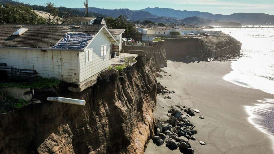 Part of a home hangs over the edge of a cliffside impacted by erosion near Palmetto Avenue in Pacifica, Calif. on Tuesday, Dec. 31, 2024. Pacifica remains one of the most vulnerable beach towns in the state to climate change. A proposed solution, managed retreat, a concept that Pacifica must slowly recede away from the coastline, has become highly political and has divided many residents in the city as officials grapple with threats from rising seas.