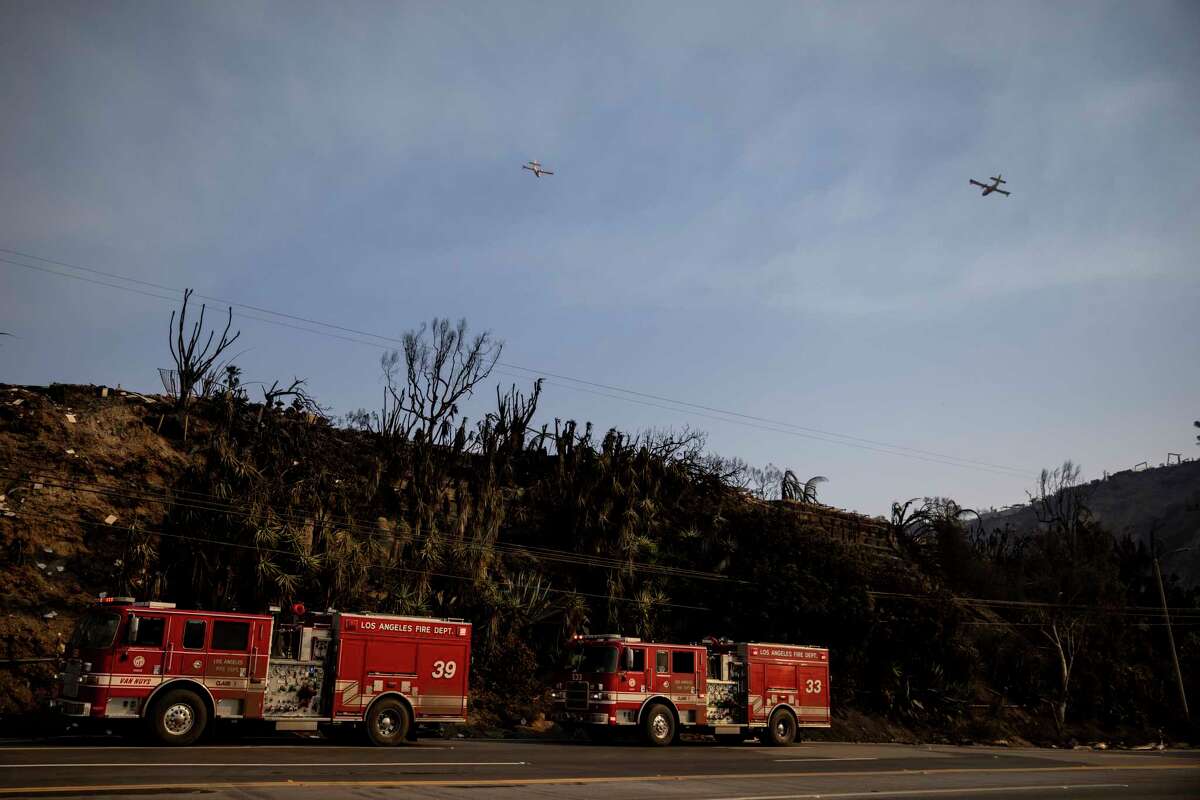 Two firefighting aircraft fly overhead during the Palisades Fire in Pacific Palisades, Calif., Thursday, Jan. 9, 2025.