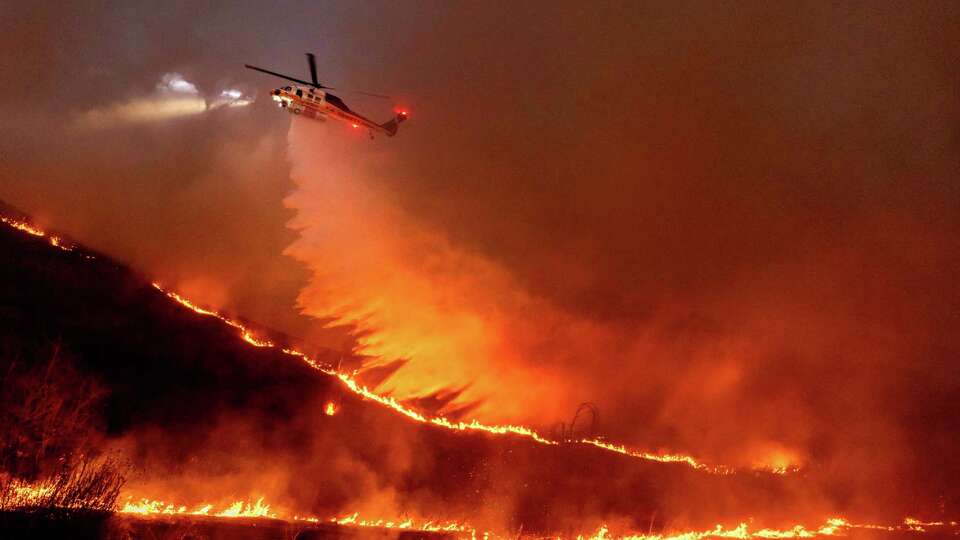 Water is dropped by helicopter on the Kenneth Fire in the West Hills section of Los Angeles, Thursday, Jan. 9, 2025. (AP Photo/Ethan Swope)