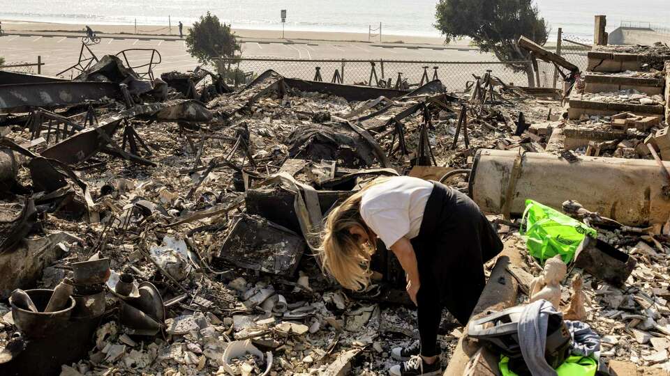 Lisa Anderson reacts as she works to recover items from her home destroyed by the Palisades Fire in Pacific Palisades, Calif., Thursday, Jan. 9, 2025.