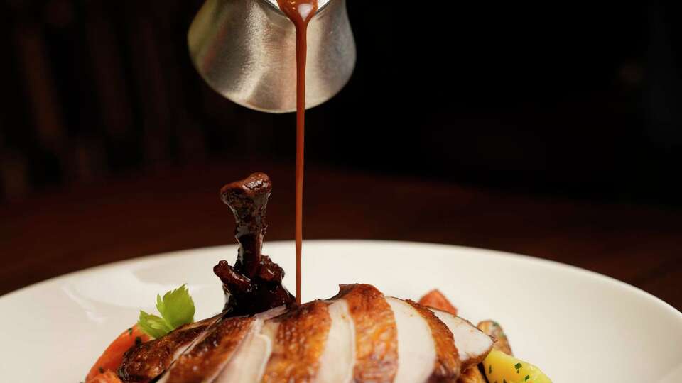 Chef Partner of Hotel Saint Augustine Aaron Bludorn pours the sauce over Perseid’s Cog au Vin Friday, Jan. 10, 2025 at Hotel Saint Augustine in Houston.