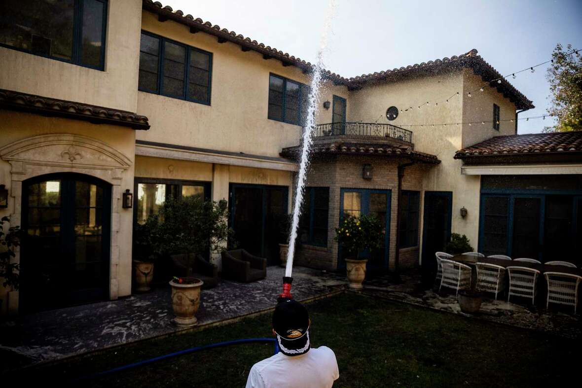 Neil Desai hoses down his intact home after successfully defending it against the Palisades Fire in Pacific Palisades, Calif., Friday, Jan. 10, 2025.