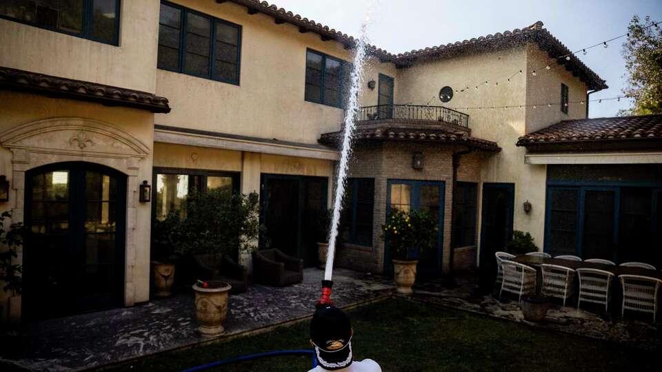 Neil Desai hoses down his intact home after successfully defending it against the Palisades Fire in Pacific Palisades, Calif., Friday, Jan. 10, 2025.