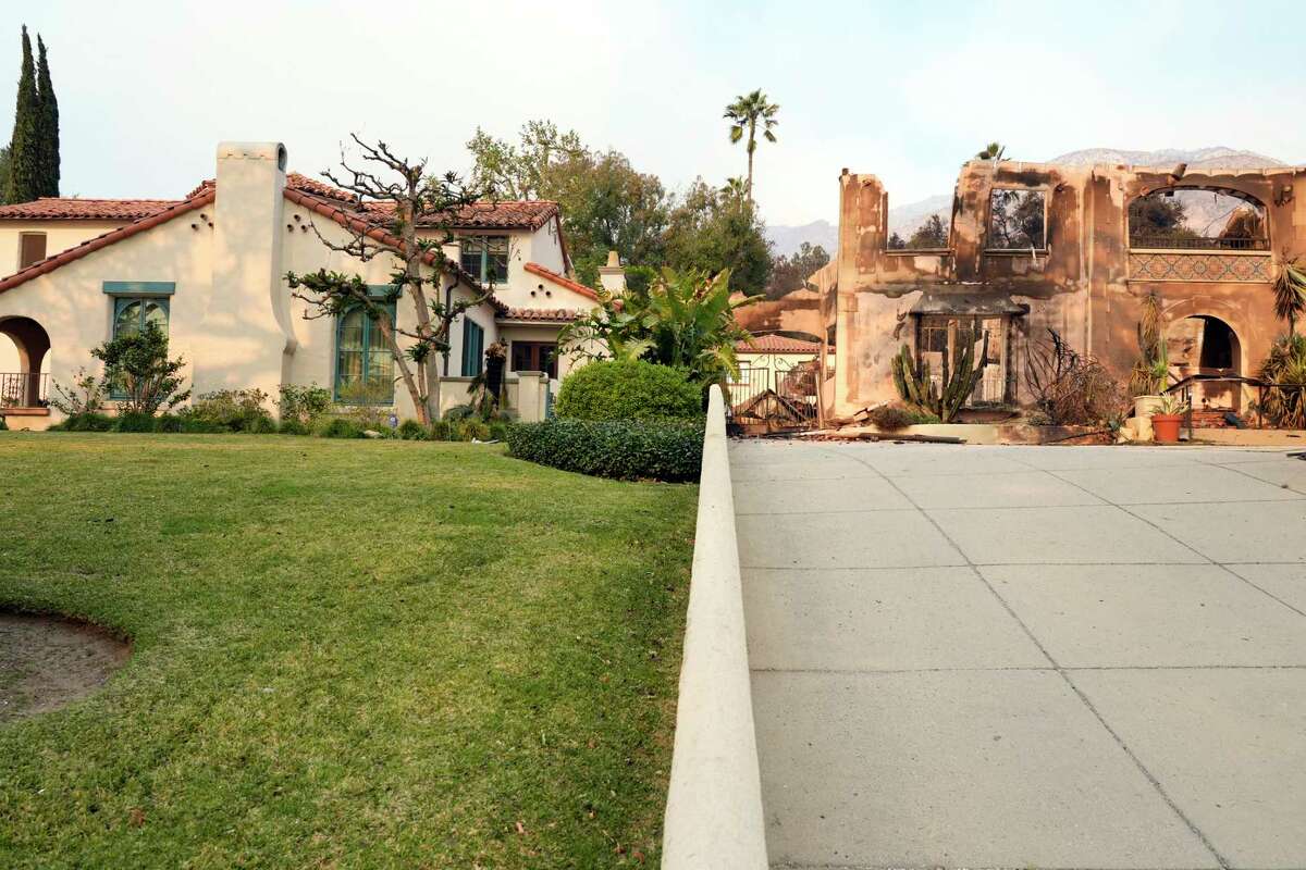 The front exterior of the Walsh House featured in the television series 'Beverly Hills 90210,' left, stands undamaged next to a house charred by the Eaton Fire, Thursday, Jan. 9, 2025, in Altadena, Calif. (AP Photo/Chris Pizzello)