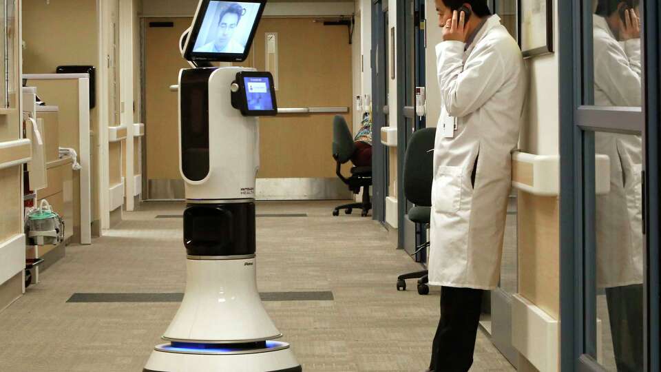 In this photo taken Wednesday, Nov. 6, 2013 Dr. Alan Shatzel, medical director of the Mercy Telehealth Network, is displayed on the monitor RP-VITA robot as he waits to confer with Dr. Alex Nee at Mercy San Juan Hospital in Carmichael, Calif. The robots enable physicians to have 'beam' themselves into hospitals to diagnose patients and offer medical advice during emergencies. (AP Photo/Rich Pedroncelli)