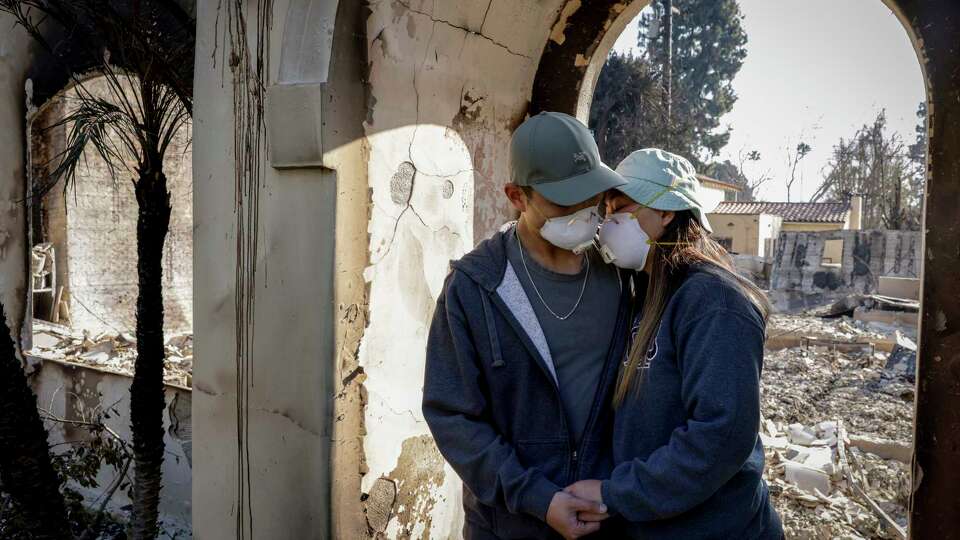 Gene Huang Lee, 32, embraces his wife, Demi Choo, 31, outside their destroyed home in Altadena, Calif. on Friday, Jan. 10, 2024. The couple was out of the country when they received news that flames from the Eaton Fire destroyed their home. The couple moved to the Altadena neighborhood in 2021. “We bought a house, and then we got married that year,” said Choo. “We were so excited, because it's our first home together…It was going to be our forever home.”