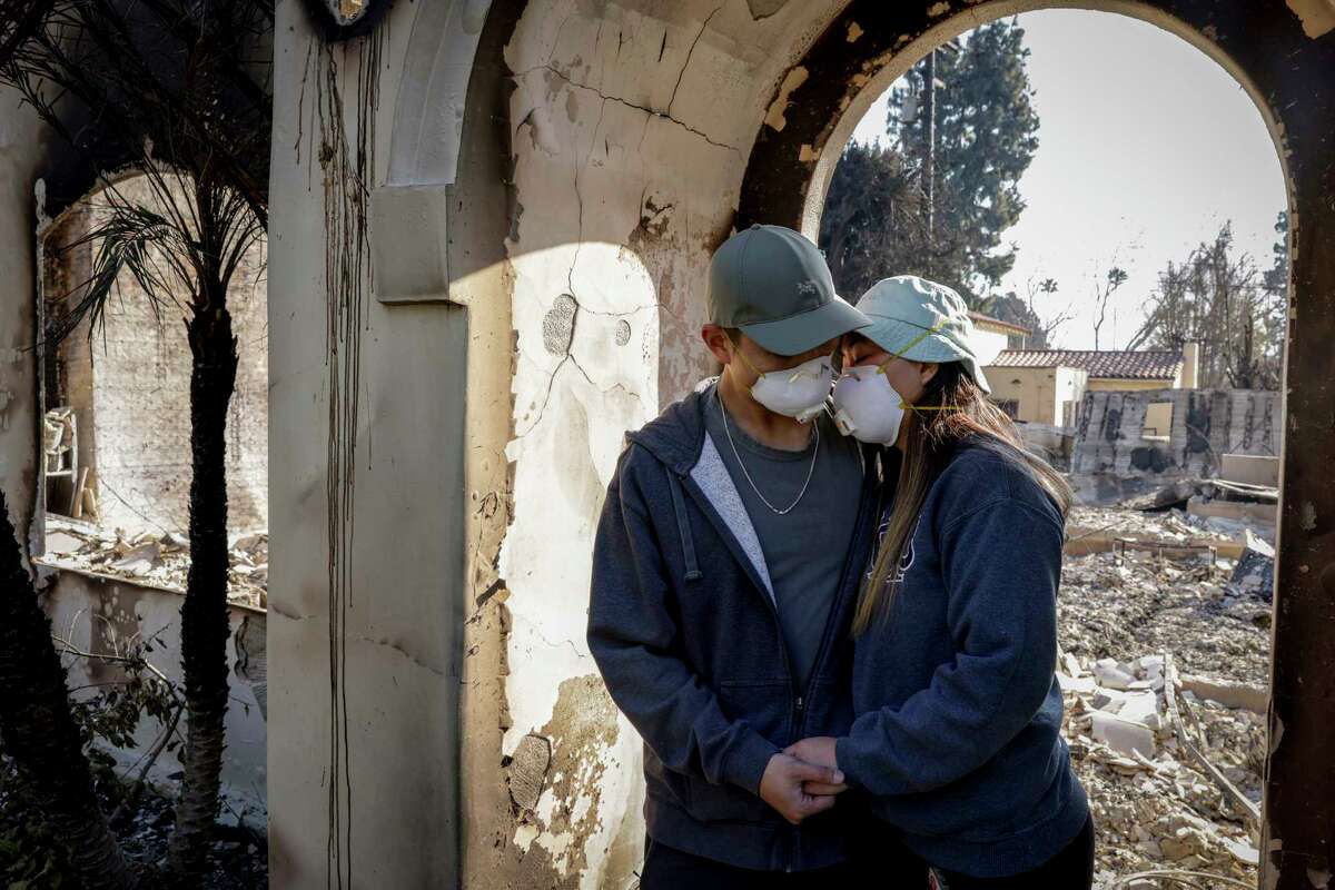 Gene Huang Lee, 32, embraces his wife, Demi Choo, 31, outside their destroyed home in Altadena, Calif. on Friday, Jan. 10, 2024. The couple was out of the country when they received news that flames from the Eaton Fire destroyed their home. The couple moved to the Altadena neighborhood in 2021. “We bought a house, and then we got married that year,” said Choo. “We were so excited, because it's our first home together…It was going to be our forever home.”