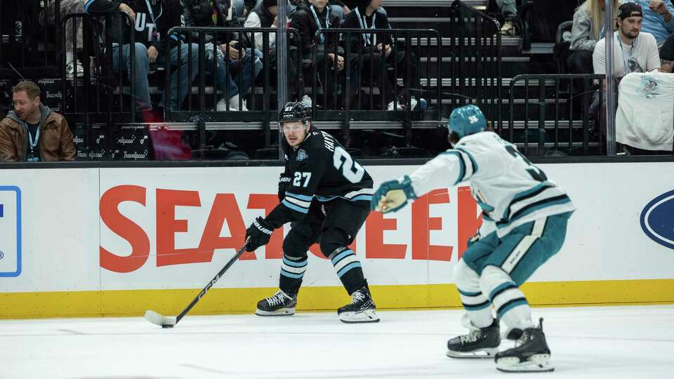 Utah Hockey Club center Barrett Hayton (27) moves the puck against San Jose Sharks defenseman Mario Ferraro (38) during the first period of an NHL hockey game Friday, Jan. 10, 2025, in Salt Lake City.