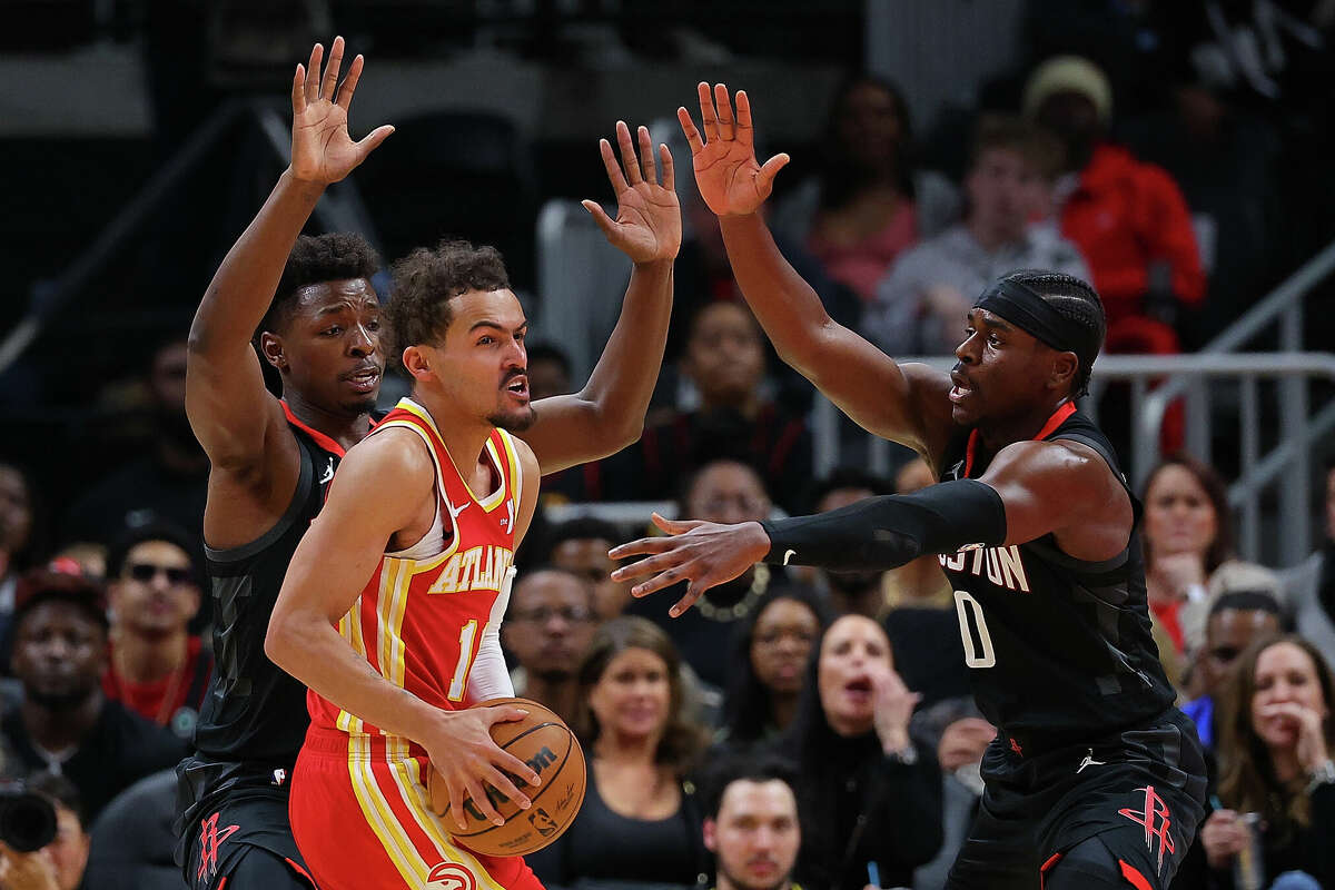 Trae Young of the Atlanta Hawks is trapped by Jae'Sean Tate and Aaron Holiday of the Houston Rockets during the third quarter at State Farm Arena on February 10, 2024 in Atlanta, Georgia.