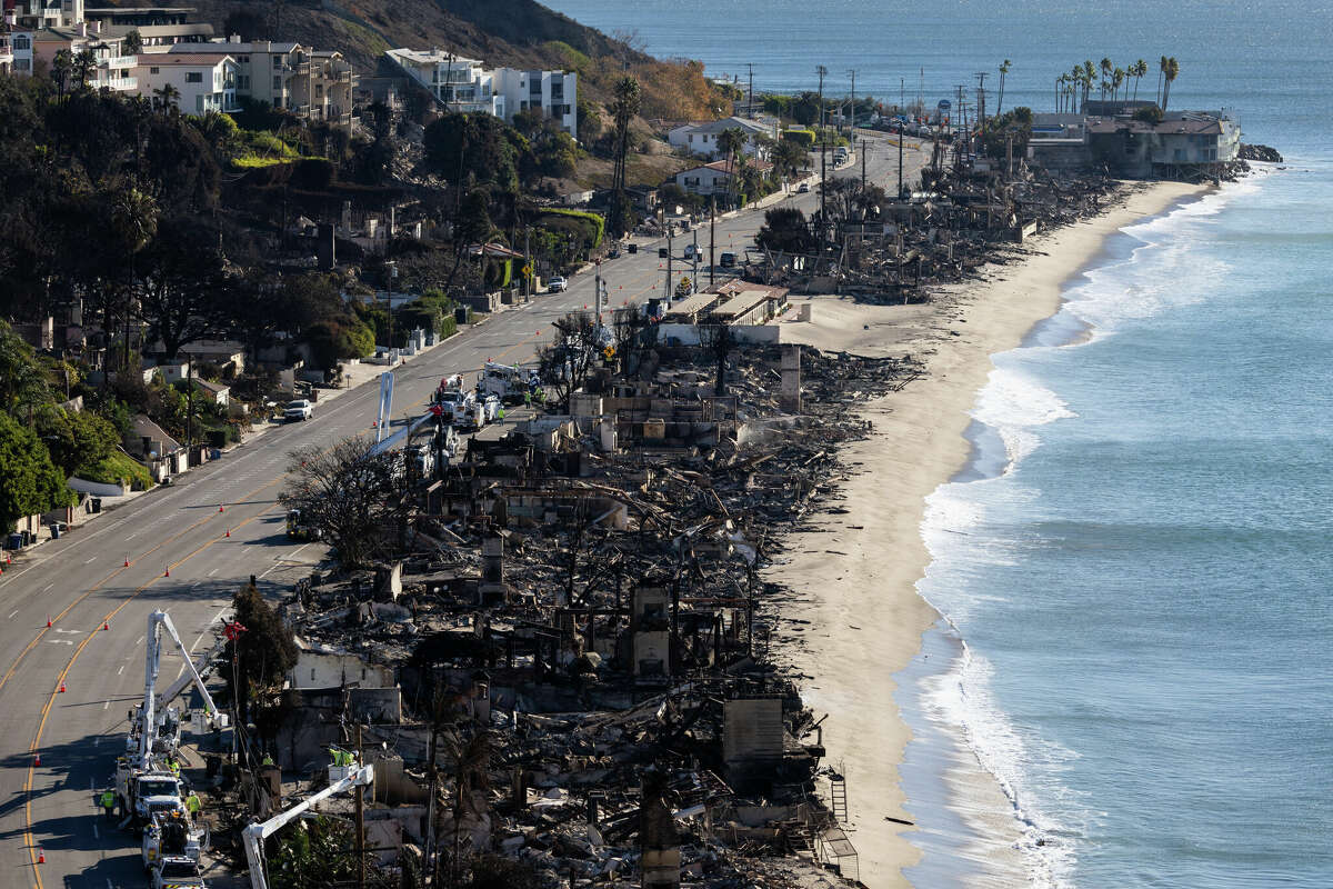 Vehicles run on the Palisades section of Pacific Coast Highway along scorched structures and trees by wildfires on January 12, 2025 in Los Angeles, California.