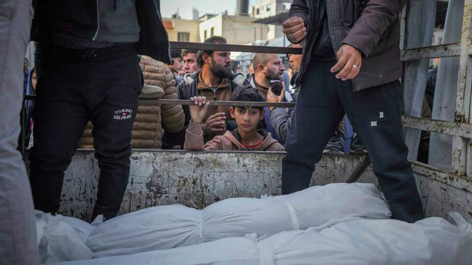 A boy looks at the bodies of Palestinians killed in the Israeli bombardment of the Gaza Strip as they are brought for burial at Al-Aqsa Hospital in Deir al-Balah, Wednesday, Jan. 15, 2025.