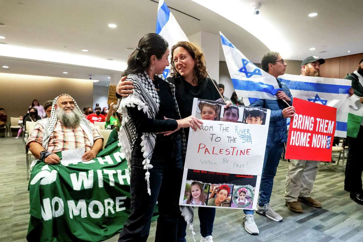 A pro-Israel demonstrator, right, embraces a pro-Palestinian demonstrator during a Richmond City Council meeting on Tuesday, Oct. 24, 2023, in Richmond, Calif. The Council was scheduled to vote on a resolution calling Israel's occupation of Gaza an apartheid regime and its war against Hamas a campaign of ethnic cleansing.