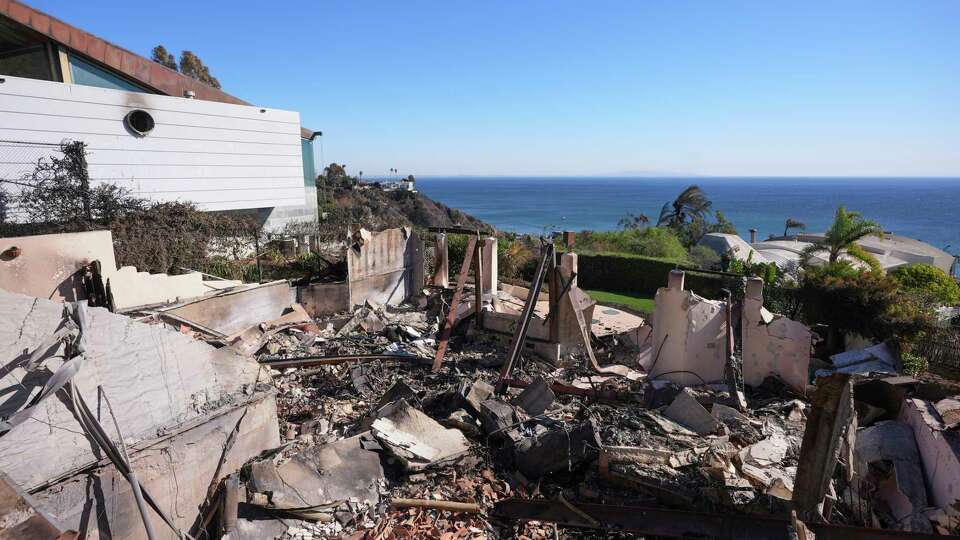 Debris from a home destroyed by the Palisades Fire is seen next to a home still standing in Malibu, Calif., Sunday, Jan. 12, 2025. (AP Photo/Mark J. Terrill)