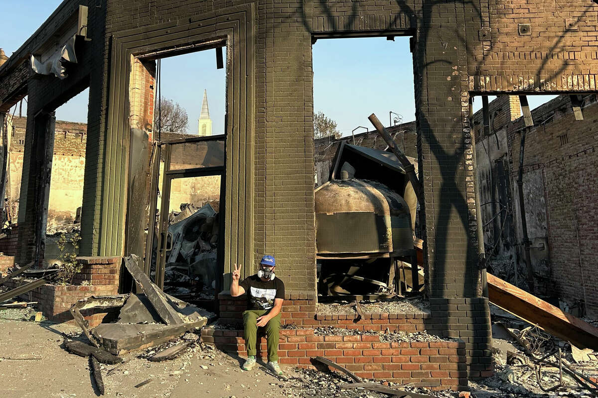 Kevin Hockin, the owner of Side Pie, a pizzeria in Altadena, Calif., stands in front of his shop burned down during last week's Eaton fire. 