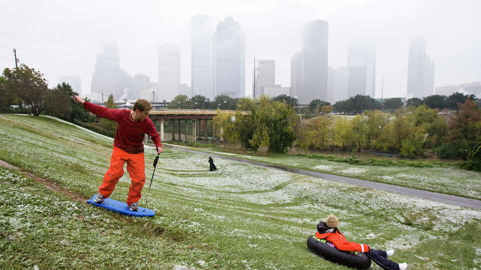 Chris Lewis (cq), of Houston, left, rides a boogie board turned snow sled down a snow slicked hill with Lauren Lewis (cq), of Houston, Friday, Dec. 4, 2009, at Eleanor Tinsley Park in Houston. ( Nick de la Torre / Chronicle )