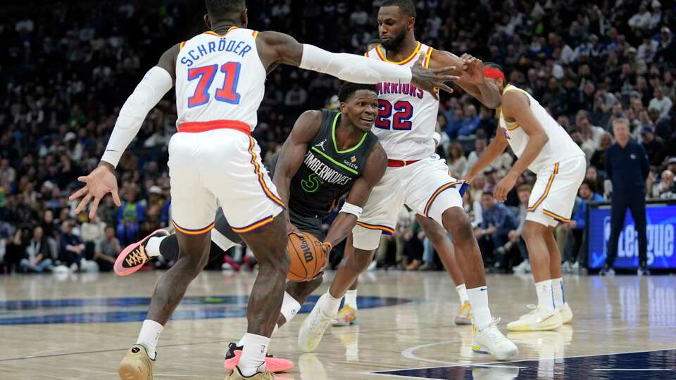 Minnesota Timberwolves guard Anthony Edwards (5) works toward the basket as Golden State Warriors guard Dennis Schroder (71) and forward Andrew Wiggins (22) defend during the second half of an NBA basketball game, Wednesday, Jan. 15, 2025, in Minneapolis. (AP Photo/Abbie Parr)