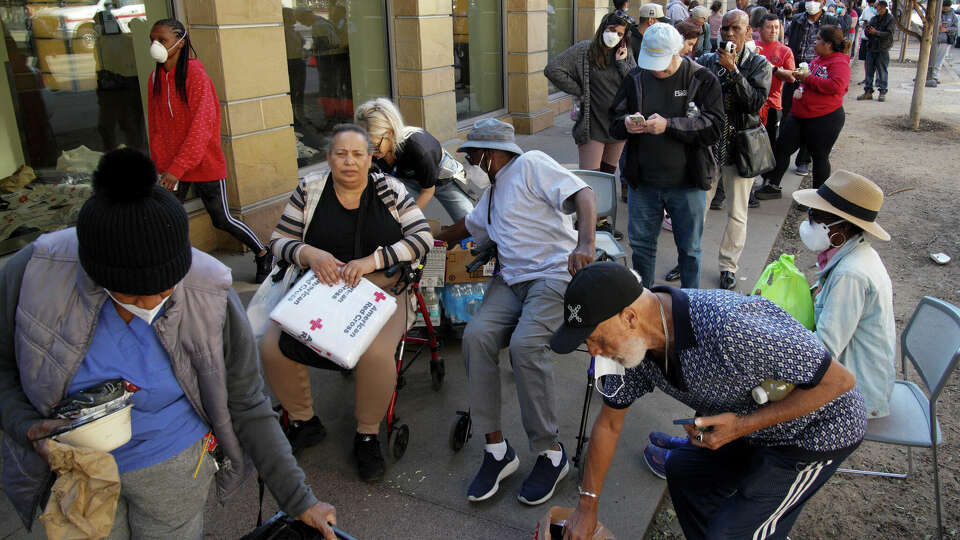 People wait in line at an aid center for those affected by wildfires at the Pasadena Convention Center Friday, Jan. 10, 2025 in Pasadena, Calif. (AP Photo/Richard Vogel)