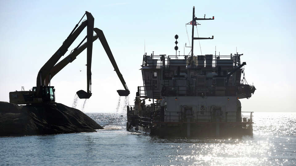 Excavators transfer sand from the eastern sandbar along the mouth of Southport Harbor onto the U.S. Army Corps of Engineers Dredge Murden, in Fairfield, Conn. Jan. 17, 2025.