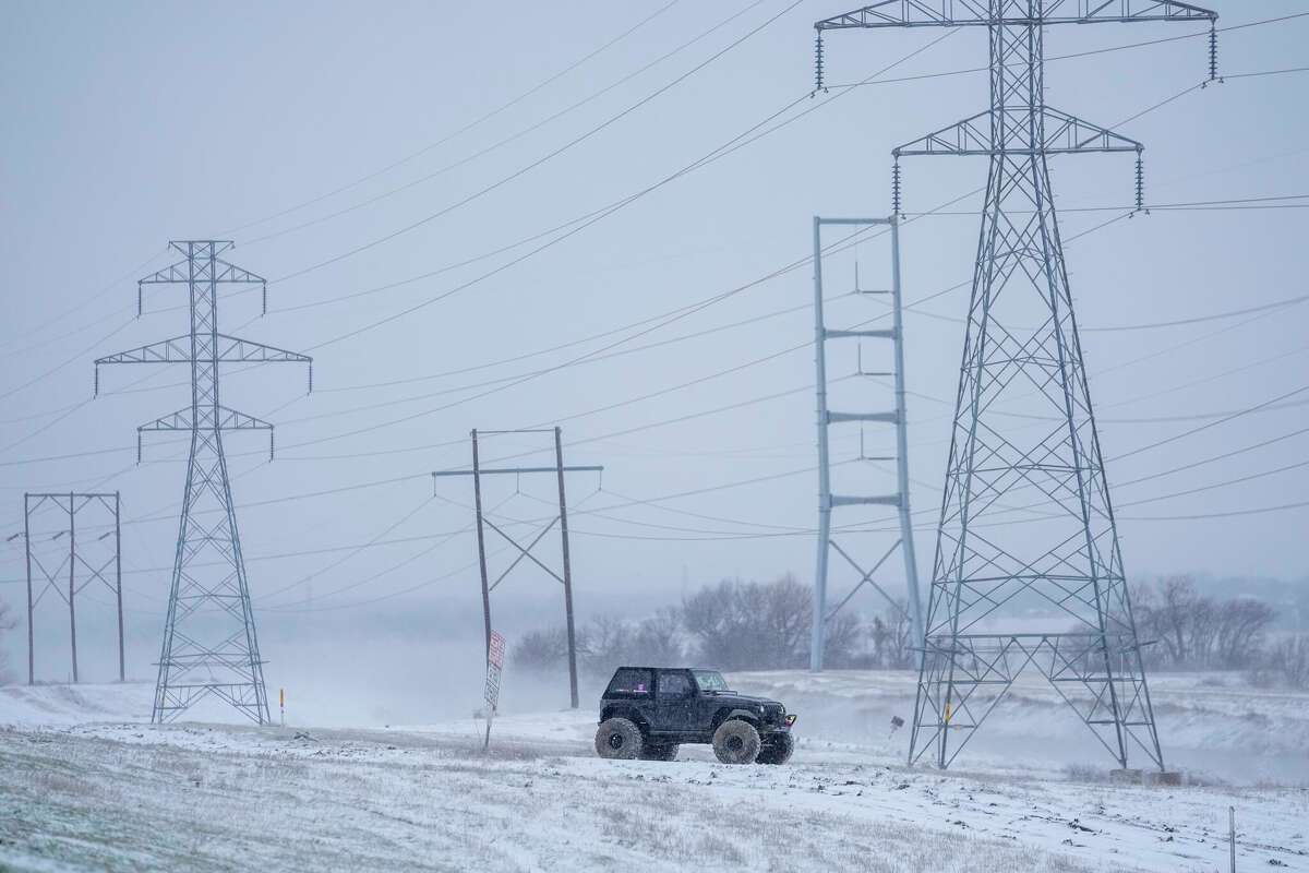 A vehicle off-roads on a snow-covered area along Mountain Creek Lake during a winter storm, Monday, Jan. 15, 2024, in Grand Prairie, Texas. (AP Photo/Julio Cortez)