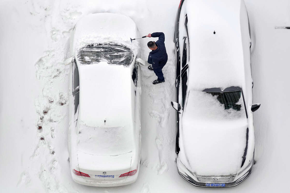 Snow blankets cars in a parking lot. Clearing snow off a car can be an arduous exercise when winter comes. 