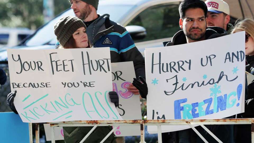 Spectators hold up signs near the finish line during the Chevron Houston Marathon Sunday, Jan. 19, 2025 in Houston.