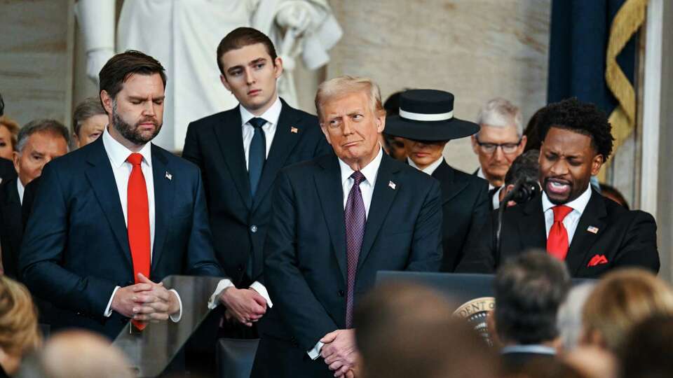 WASHINGTON, DC - JANUARY 20: Vice President JD Vance, Barron Trump and President Donald Trump listen to Senior Pastor Lorenzo Sewell speak after Trump was sworn in at his inauguration in the U.S. Capitol Rotunda on January 20, 2025 in Washington, DC. Donald Trump takes office for his second term as the 47th President of the United States.