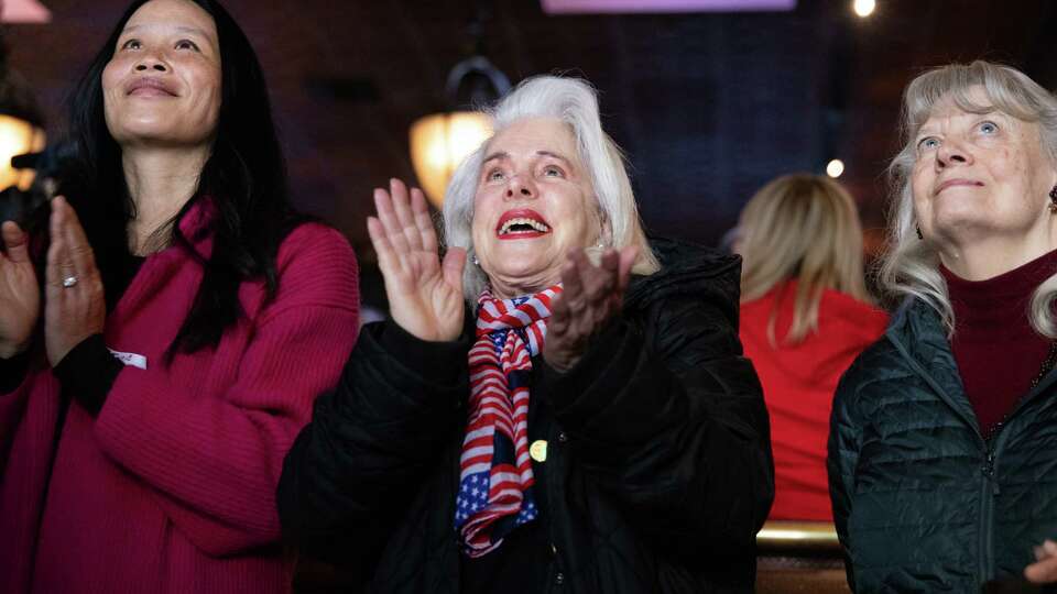 Lina Pritchard, center, claps after the national anthem at a GOP inauguration watch party at Harry's Bar in San Francisco on Monday, Jan. 20, 2025. Donald Trump is being sworn in as the 47th President of the United States.