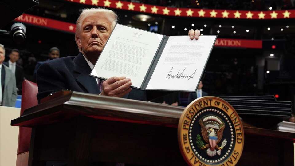 President Donald Trump signs an executive order as he attends an indoor Presidential Inauguration parade event at Capital One Arena, Monday, Jan. 20, 2025, in Washington.