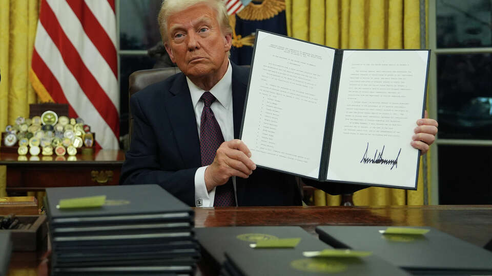 President Donald Trump holds up an executive order commuting sentences for people convicted of Jan. 6 offenses in the Oval Office of the White House, Monday, Jan. 20, 2025, in Washington. (AP Photo/Evan Vucci)