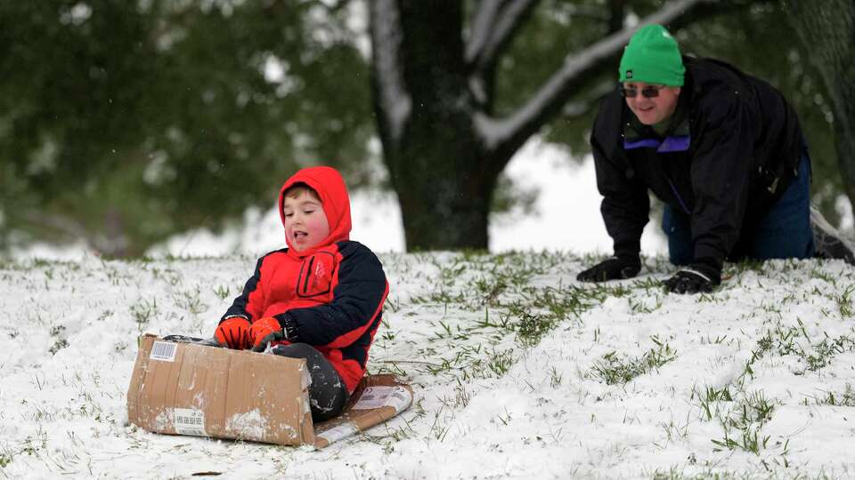 Faolan Benoit, 8, sleds with a push from his dad, Casey Benoit in a neighborhood park Tuesday, Jan. 21, 2025, in Spring.