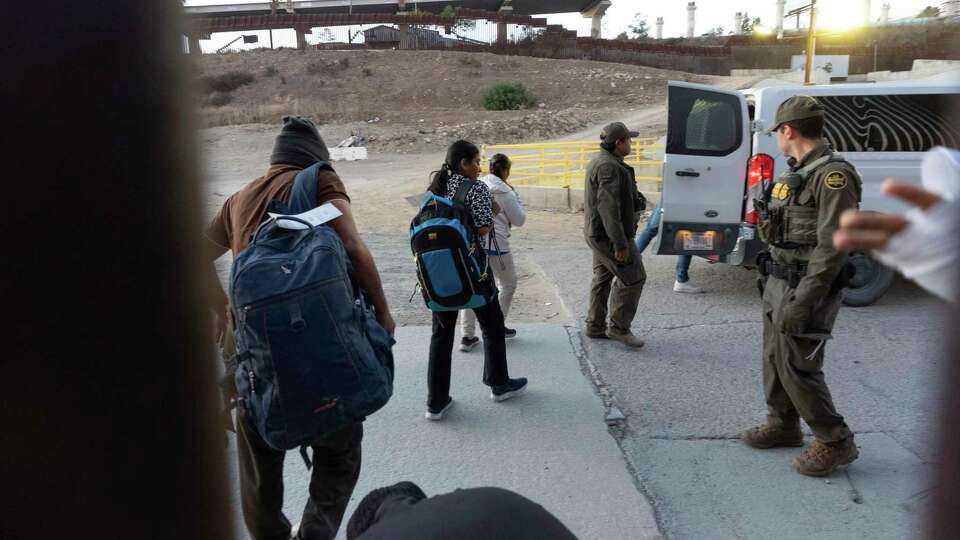 Migrants make their way to a Border Patrol van after crossing illegally and waiting to apply for asylum between two border walls separating Mexico and the United States, Tuesday, Jan. 21, 2025, in San Diego.