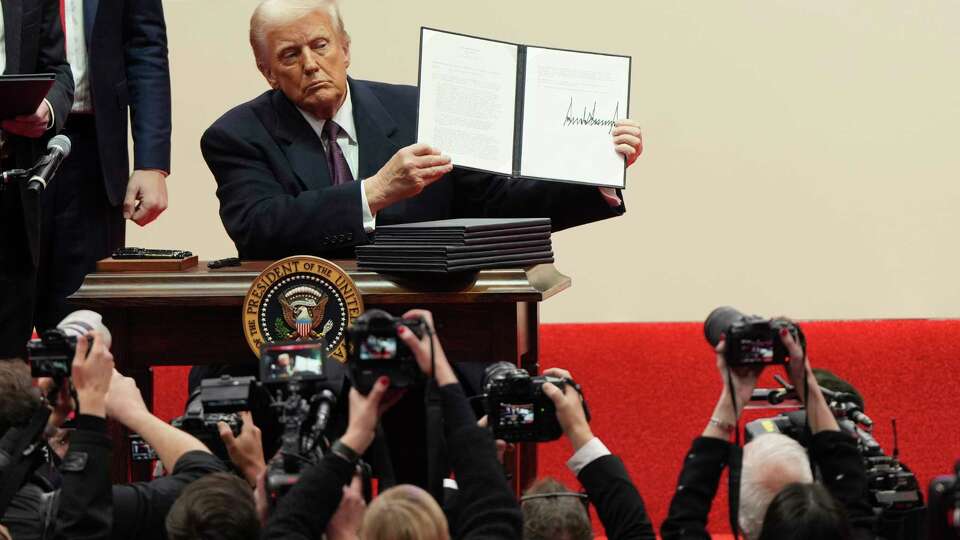 President Donald Trump holds up an executive orders after signing it at an indoor Presidential Inauguration parade event in Washington, Monday, Jan. 20, 2025. (AP Photo/Matt Rourke