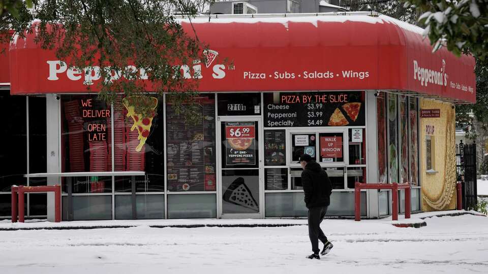 A person walks by Pepperoni's on Montrose Boulevard during the snow Tuesday, Jan. 21, 2025 in Houston.