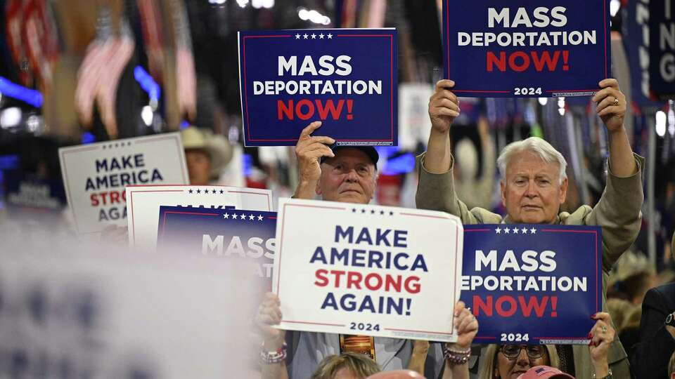 Attendees hold signs reading 'mass deportations now!' during the third day of the 2024 Republican National Convention at the Fiserv Forum in Milwaukee, Wisconsin, on July 17, 2024.