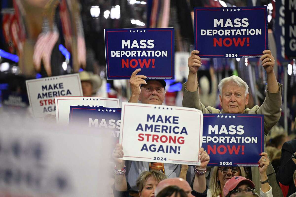 Attendees hold signs reading 'mass deportations now!' during the third day of the 2024 Republican National Convention at the Fiserv Forum in Milwaukee, Wisconsin, on July 17, 2024.