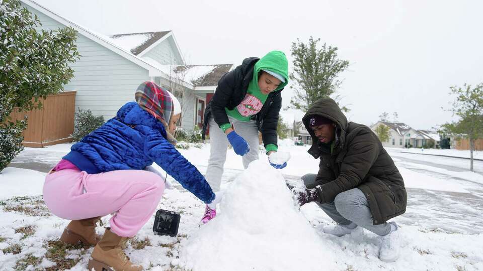 From left, Lawren Lacy, her daughter Bailey Stoker, 14, and Paris Washington build a snow man in the Balmoral neighborhood in Atascocita, TX on Tuesday January 21, 2025.