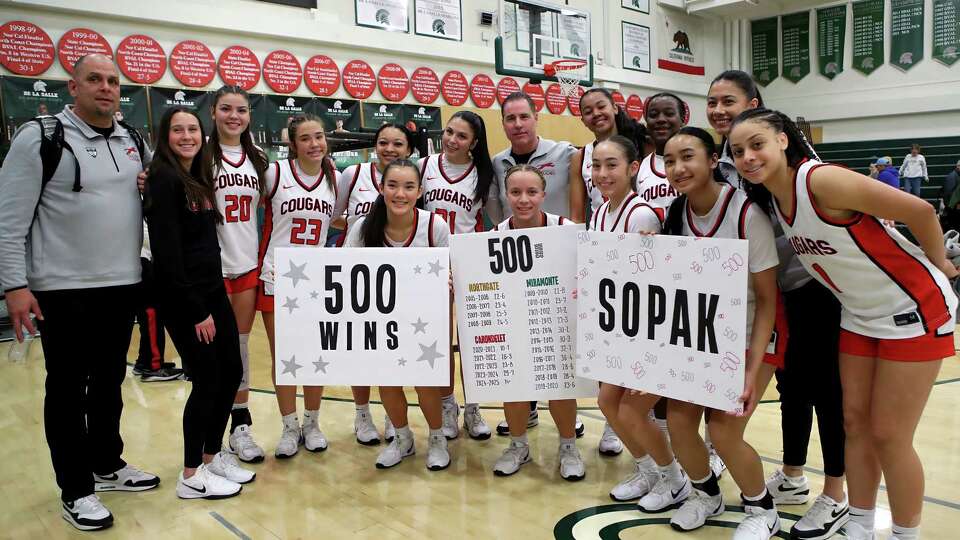 Carondelet-Concord girls basketball coach Kelly Sopak (back row, middle) is surrounded by his players after picking up career win No. 500.