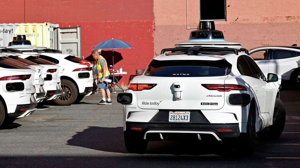 A person is seen working next toa Waymo car in a lot at 350 Pacific Avenue on Wednesday, January 15, 2025, in San Francisco,Calif.