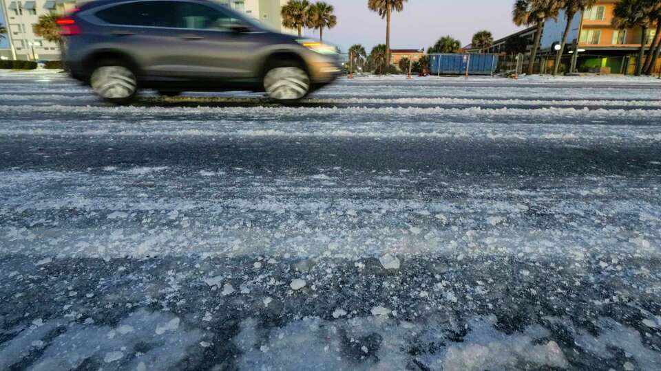 Vehicles make they way along the ice-covered Seawall Blvd. in the aftermath of an icy winter storm on Wednesday, Jan. 22, 2025 in Galveston.