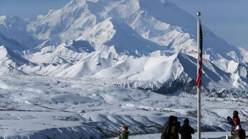 FILE - People stand at the Eielson Visitor Center with a view of North America's tallest peak, Denali, in the background, Sept. 2, 2015, in Denali National Park and Preserve, Alaska. (AP Photo/Becky Bohrer, file)