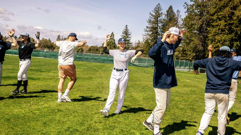 Marika Lyszczyk, a sophomore pitcher on the Sonoma State baseball team, center, stretches during practice in Rohnert Park, Calif., Friday, March 24, 2023. Lyszczyk is the first female baseball player at the school and California Collegiate Athletic Association.