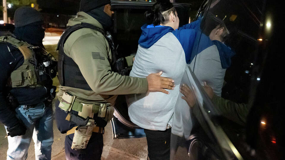 U.S. Immigration and Customs Enforcement officers help a detained person into a car, Monday, Jan. 27, 2025, in Silver Spring, Md.