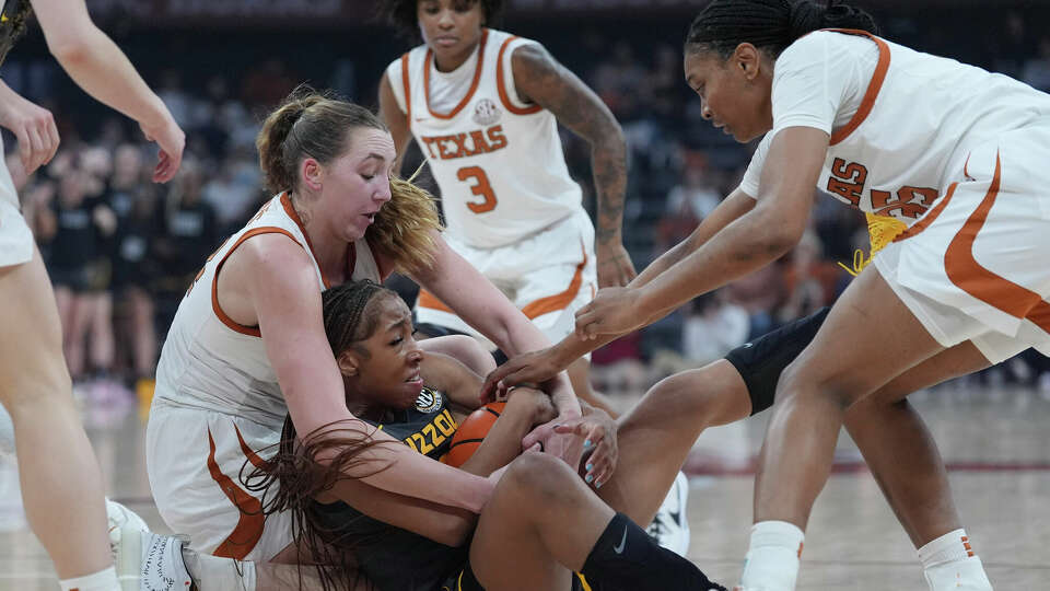 Missouri guard Nyah Wilson, center, scrambles for the ball with Texas forwards Taylor Jones, left, and Madison Booker, right, during the first half of an NCAA college basketball game in Austin, Texas, Thursday, Jan. 30, 2025. (AP Photo/Eric Gay)