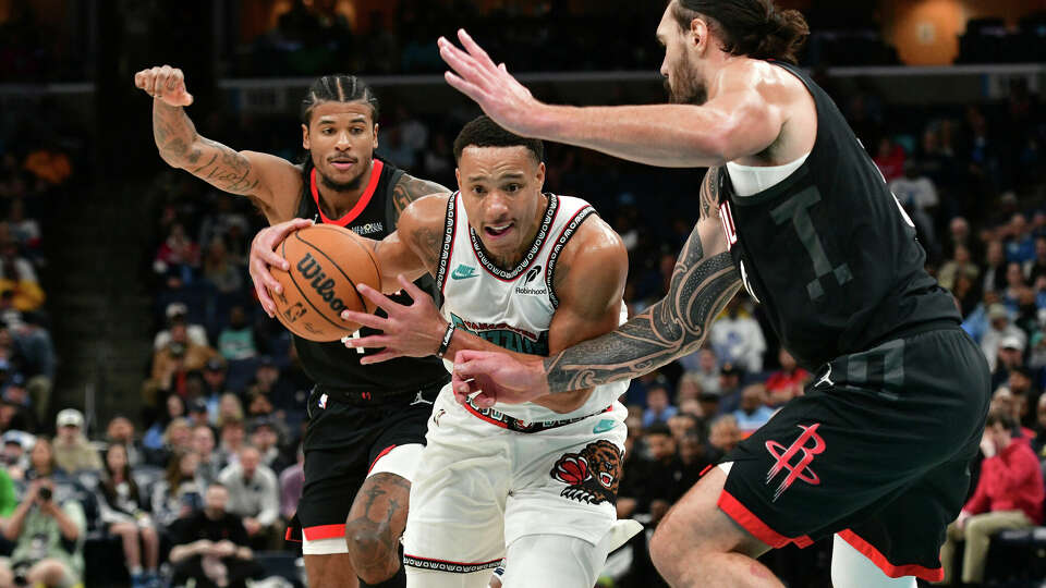 Memphis Grizzlies guard Desmond Bane, center, handles the ball between Houston Rockets center Steven Adams, right, and guard Jalen Green, left, in the second half of an NBA basketball game Thursday, Jan. 30, 2025, in Memphis, Tenn. (AP Photo/Brandon Dill)