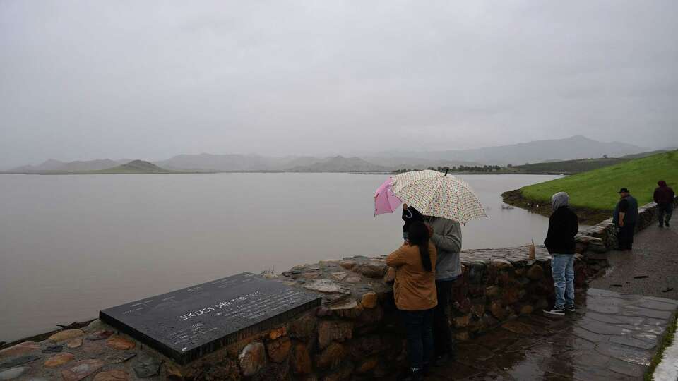 People look on at a full pool of water behind Schafer Dam, forming Lake Success on the Tule River in the Central Valley during a winter storm in Tulare County east of Porterville, California on March 21, 2023. Federal records show that water releases from Terminus Dam at Lake Kaweah and Schafer Dam at Lake Success jumped early Friday morning, Jan. 31, 2025, in accordance with a directive from President Donald Trump.