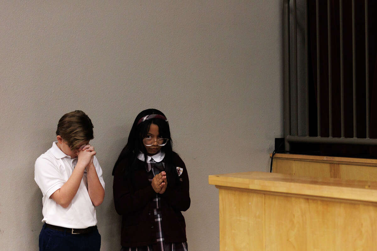 Students from San Antonio Christian School pray before elected officials, including the governor, speak at an event the school hosted to promote school vouchers.