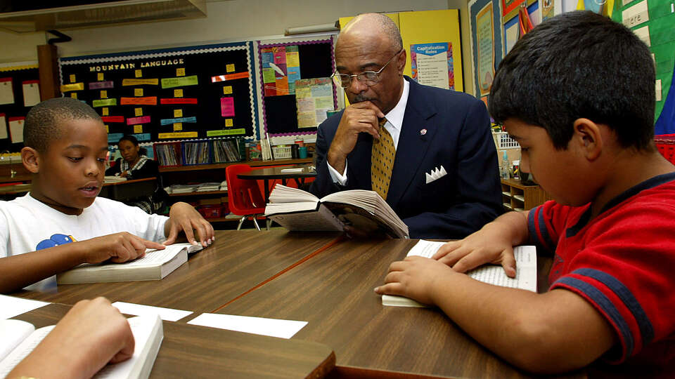 U.S. Secretary of Education Rod Paige (center) picks up a book with Aldine ISD's Evelyn S. Thompson Elementary School third graders Eric Olivars (right 9yrs) and Jonathan Deams (left 9yrs) May 09,2003.Paige was on hand for a speach annoucing that Texas schools will recieve $532 million dollars in federal support over the next six years. James Nielsen