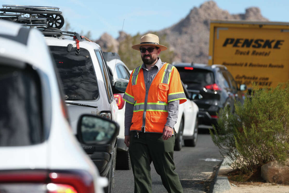 A National Park Service ranger directs traffic at an entrance to Joshua Tree National Park, to prevent traffic from backing up into the adjacent community, on February 19, 2025 in Joshua Tree, California. 