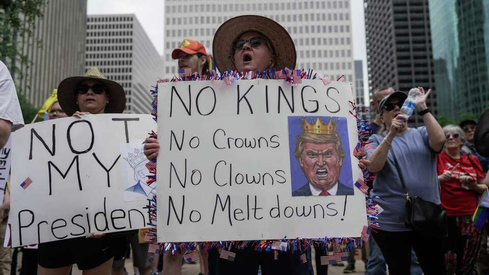 People hold up signs alongside people joining the 50501 Movement, a group opposed to the actions of President Donald Trump's administration, for a rally at City Hall on Saturday, April 19, 2025 in Houston.